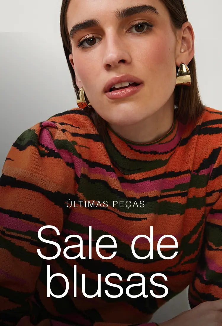 Mulher vestindo blusa estampada listrada em tons terrosos e rosados, com brincos dourados e olhar sofisticado — banner “Sale de blusas” AlmaChic.
